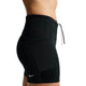 En kvinde ses fra taljen til midt på låret iført Nike ACG High-Waisted 4" løbeshorts i Black/Summit White med en synlig sidelomme og Nike-logoet på en almindelig hvid baggrund.