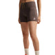 En person står foran en hvid baggrund iført Nike ACG High-Waisted 4″ løbeshorts til kvinder i farverne Ironstone/Cave Stone/Summit White, med et lille hvidt logo på venstre ben. Personens ansigt kan ikke ses.