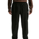 En person iført løstsiddende Nike ACG Trailwind Waterproof Pants til mænd i Black/Summit White, med elastisk linning og et lille hvidt logo på venstre lår, sammen med en langærmet brun top. Billedet er beskåret ved skuldre og ankler.