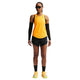 En person i lysegul ærmeløs sportstop, sort Nike Nk Arswft Dfadv 3In Short 26 (Dame, Black/White/White), sorte ærmer, knæhøje sokker, gule løbesko og solbriller står på en hvid baggrund.