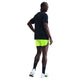 En person står med ryggen til og kigger sig over skulderen i en sort trøje, Nike Dri-FIT ADV 4" Brief-Lined Running Shorts for men (Volt/Black), sorte sokker og hvide sportssko på en hvid baggrund.