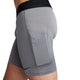 Et nærbillede fra siden viser en person iført Nike Dri-FIT Fitness Shorts, Herre, Smoke Grey/Black med sort linning og en stor lårlomme. Nike-logoet nær kanten fremhæver shortsens slanke, atletiske design.