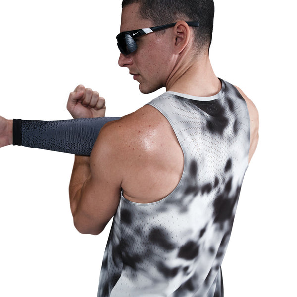 En mand med solbriller strækker sin højre arm ud over brystet iført Nike Dri-FIT Adv Running Tank Top til herrer i sort/sort/reflekterende sølv. Den hvide baggrund fremhæver den atletiske stil.