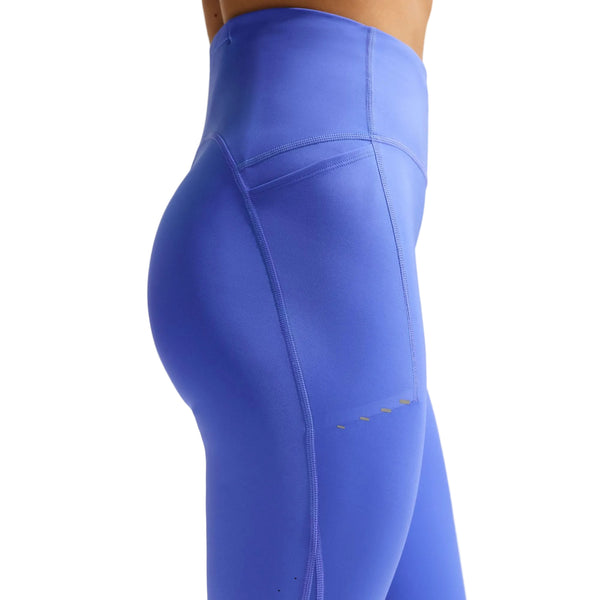 En person ses fra midt på torsoen til øverst på låret iført Nike Nk Df Swift Hr 7/8 Tight-leggings til kvinder i safir/reflekterende sølv, med synlige syninger og en sidelomme, på en almindelig hvid baggrund.