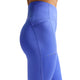 En person ses fra midt på torsoen til øverst på låret iført Nike Nk Df Swift Hr 7/8 Tight-leggings til kvinder i safir/reflekterende sølv, med synlige syninger og en sidelomme, på en almindelig hvid baggrund.