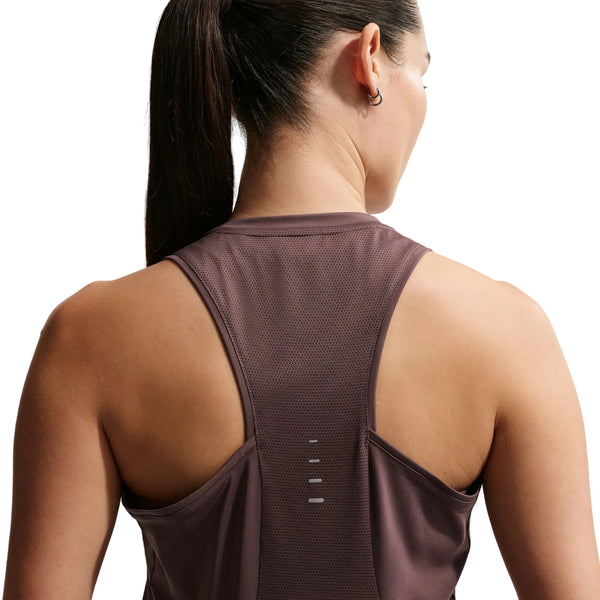 En kvinde med mørkt hår i hestehale ses bagfra iført Nike Nk Swift Df Tank Top til kvinder i Tattoo/Reflective Silv - en ærmeløs, åndbar træningstop med meshstof og refleksstriber ned langs midten.