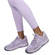 En kvinde er iført lilla Nike One High Waist 7/8 Tights, fotograferet fra knæene og ned med matchende lilla Nike-sneakers på en hvid baggrund.