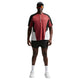 En person står med ansigtet vendt fremad iført en Nike Retro SS løbetrøje, herre, i farvekombinationen Team Crimson/sort/reflekterende sølv, kombineret med sorte shorts, hvide sokker og sneakers, en sort kasket og solbriller, foran en ensfarvet hvid baggrund.