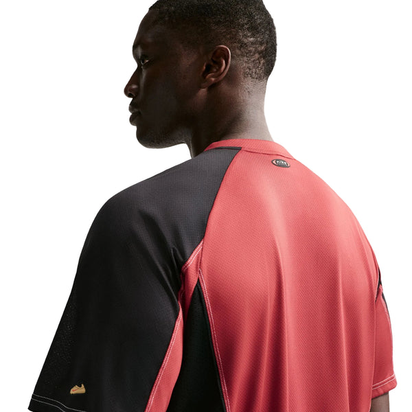 En person iført en Nike Retro SS-løbetrøje til mænd i farvekombinationen Team Crimson/Black/Reflective Silver ses set bagfra og fra siden på en hvid baggrund. Denne åndbare trøje er udstyret med Dri-FIT-teknologi, der sikrer komfort under træning.