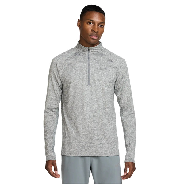 En mand iført Nike Stride Half Zip Midlayer Running Top, Herre, i Smoke Grey/HTR/Reflective Silver og matchende grå shorts står med front mod en almindelig hvid baggrund.