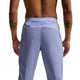 En skjorteløs person med tatoveringer står med ryggen til kameraet iført Nike Stride Repel Running Pants til herrer i Iron Purple/Indigo Haze/Reflective, med lynlåslomme i linningen og atletisk stil.