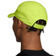 En person med korte snoninger bærer en Nike Unstructured Reflective Cap i Cyber/Anthracite/Reflective Silver med perforeret design og justerbar rem bagpå, set bagfra.