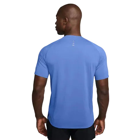 En mand med glatbarberet hoved står med ryggen til kameraet iført Nike Stride SS Running Top, Herre, Royal Pulse/Reflective Silv og sorte shorts på en almindelig hvid baggrund.