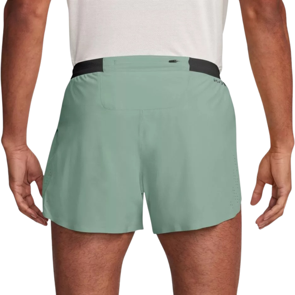 En person ses bagfra iført en hvid skjorte og Nike AeroSwift 4" Running Shorts, Herre, Steam/Black, som har en sort linning og en lille lynlåslomme til de vigtigste ting.