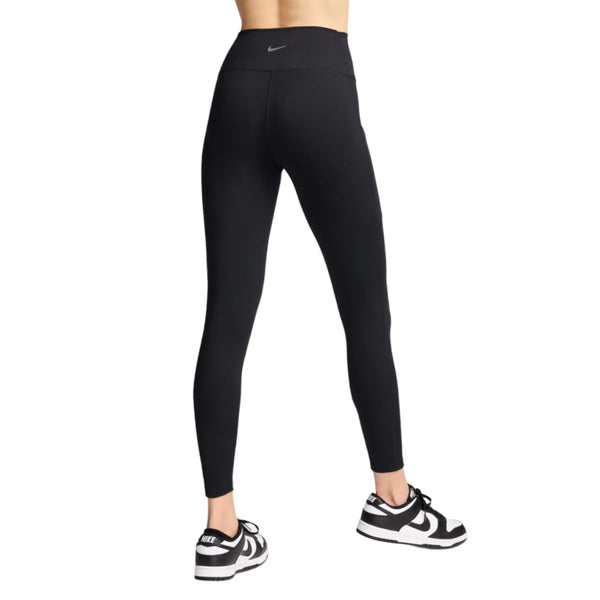 Man ser en kvinde bagfra iført sorte Nike One High-Waisted 7/8-tights og sorte Nike-sneakers, begge dele på en hvid baggrund.