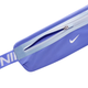 Nærbillede af Nike Slim Waistpack 4.0, Unisex, i blå, med lyseblå lynlås og hvidt Nike-logo. Den justerbare rem har hvide bogstaver på blå baggrund, som både giver stil og funktionalitet på løbeturen.