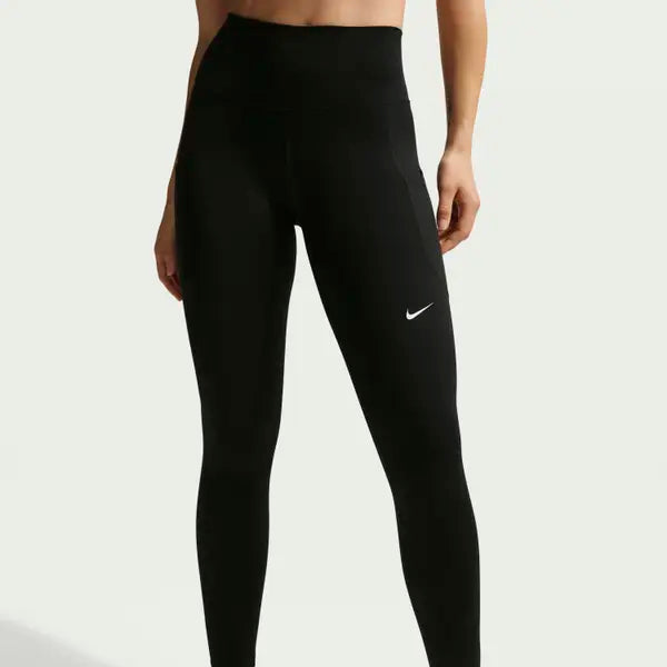 En person er iført Nike Nk Df One Hr 7/8 Pkt Tght leggings til kvinder i sort/hvid med logoet synligt på øverste venstre lår, stående mod en almindelig lys baggrund. Kun benene er vist.