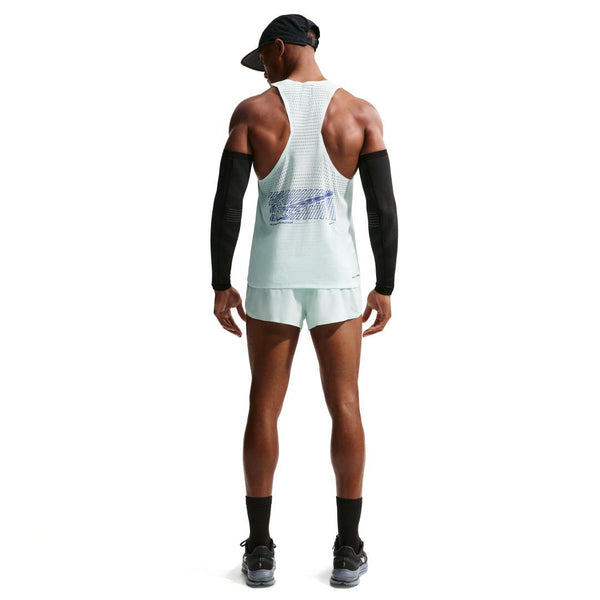 En person står med ryggen til og er iført Nike Nk Dfadv Aeroswift Gfx Snglt, Herre i Barely Green/Lapis med hvide shorts, sorte ærmer, sort kasket og sokker samt løbesko på en almindelig hvid baggrund.