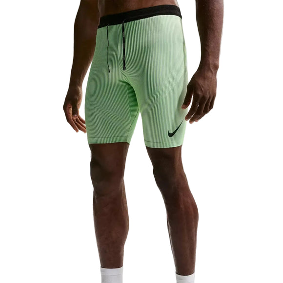 En person er iført Nike AeroSwift Running Half Tights (Herre) i Lime Blast/Steam/Light Silver/Black med ribbet stof, sort linning med snøre og et sort Nike-logo på venstre ben. Kun underkroppen og benene er synlige.