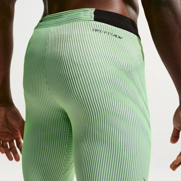 Nærbillede af en person iført Nike AeroSwift Running Half Tights, Herre, i Lime Blast/Steam/Light Silver/Black med Dri-FIT ADV-tekst nær linningen. Kun lænden, lårene og en del af den ene arm er synlige.