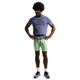 En person står med hænderne på hofterne iført en blå kortærmet skjorte, Nike AeroSwift Running Half Tights til mænd i Lime Blast/Steam/Light Silver/Black, solbriller, hvide sokker og lilla og sorte sportssko på en almindelig hvid baggrund.