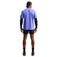 En person kigger væk og er iført en Nike Nk Dfadv Aroswft Ss Top, Herre i Sapphire/Black, sammen med sort kasket, ærmer, shorts, sokker og sportssko med pink såler på en almindelig hvid baggrund.