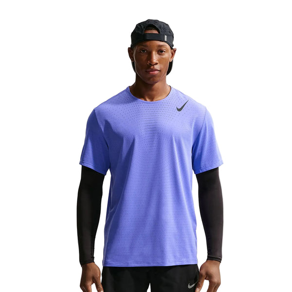 En mand iført en Nike Nk Dfadv Aroswft Ss Top i Sapphire/Black over en langærmet sort skjorte, parret med sorte shorts og en bagudvendt sort kasket, står på en almindelig hvid baggrund.