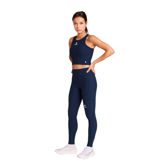 En kvinde kigger fremad med hånden på hoften, iført Saysky W Combat+ Rib Long Tights i blå og en matchende crop top, sammen med hvide sneakers. Baggrunden er helt hvid.