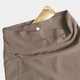 Nærbillede af Saysky W Combat+ Rib Short Tights 4" til kvinder i taupe med ribkant, høj talje med skjult lomme i linningen til en guldfolieindpakket genstand og et lille hvidt korslogo på linningen.