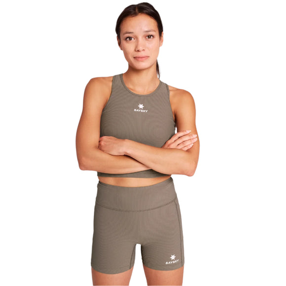 En kvinde står selvsikkert med armene over kors iført en matchende olivengrøn tanktop og Saysky W Combat+ Rib Short Tights 4" i taupe med et lille hvidt SATORY-logo.