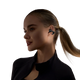 En kvinde med blondt hår i hestehale bærer sorte Shokz Open Dots One True Wireless Open-Ear Hovedtelefoner og en sort top med lynlås, mens hun kigger lidt til siden mod en almindelig hvid baggrund.