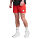 En person står på en almindelig baggrund iført en sort herre-skjorte, hvide sokker, hvide sneakers og knaldrøde Saysky Pace Shorts 5" (Herre), der afslører ben-tatoveringer som øjne på venstre knæ.