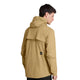 Man ser en person med kort, mørkt hår set bagfra, iført Saysky Pace Tech Jacket, Herre, Beige – en lysebrun ripstop-jakke med et sort, rektangulært mærke med et hvidt logo nederst på ryggen. Denne funktionelle træningsjakke fremhæves på en ensfarvet, hvid baggrund.