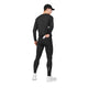 En person iført en sort kasket, en langærmet trøje og Saysky Pace+ lange tights, Herre, Sort står med ryggen til og holder en telefon i baglommen. Outfittet består desuden af hvide sportssko, og de lange tights er forsynet med et lille Saysky-logo.