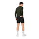 En mand set bagfra, iført sorte Pace Shorts 5″, Herre, med en baglomme, hvide sokker og hvide sneakers.