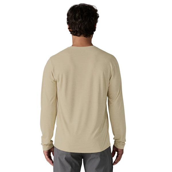 En mand med kort, mørkt hår ses bagfra iført Patagonia L/S Cap Cool Daily Graphic Shirt, Herre, Earlylines/Pumice X-Dye og grå bukser. Hans arme er afslappede ved siden af ham mod en almindelig hvid baggrund.