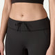 En kvinde iført Patagonia Peak Mission Tights 27" i sort, vist fra midten af torsoen til det øverste af lårene mod en neutral baggrund.