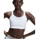 En person iført On Performance Bra, Dame, White med grå sportsbukser står selvsikkert på en almindelig hvid baggrund, klar til løb eller træning.