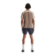En person står med front mod kameraet iført en On Performance-T til mænd i farven Desert/Cinder, sammen med mørkeblå shorts, hvide sokker og lyse sportssko på en hvid baggrund.