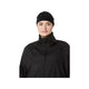 En person, der bærer et Asics Performance-pandebånd (unisex) i farven Performance Black samt en sort jakke med lynlås, står med ansigtet vendt fremad foran en ensfarvet hvid baggrund. Vedkommende har et neutralt udtryk, og billedet viser vedkommende fra brystet og opefter, hvilket tyder på, at vedkommende er klar til at løbe eller udøve en anden sportsaktivitet.
