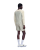 En mand står med ryggen til og har en On Performance Long-T til mænd i farvekombinationen Hare/Brume på samt matchende shorts i åndbart materiale, hvidt par sokker og hvide sportssko. Baggrunden er ensfarvet hvid.