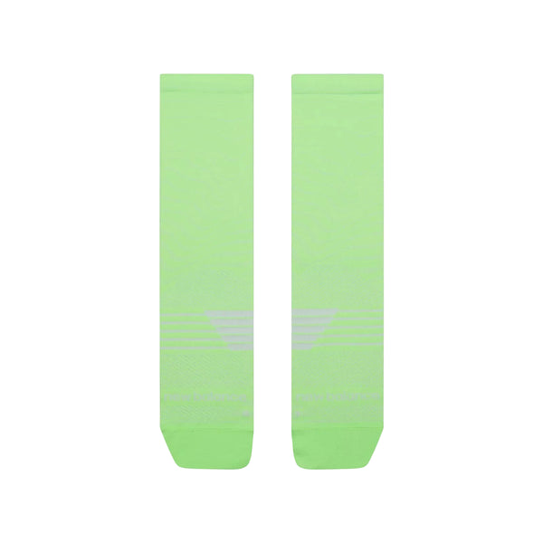 Et par New Balance Pro Run Crew Socks, unisex i Afterglow lysegrøn med diskrete hvide vandrette striber nær anklen, vises side om side på en hvid baggrund.