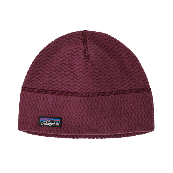 Patagonia R1 Air Beanie i farven Berry Fig er en unisex-strikhuve med et struktureret zigzagmønster og et lille rektangulært Patagonia-logo på forsiden. Den vises på en ensfarvet hvid baggrund.