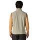 Der ses en person set bagfra, der bærer en Patagonia R1 Air Vest, Herre, i farven Pelican, over en langærmet, beige skjorte og mørke bukser. Den ærmeløse vest har et lysbeige mønster med struktur og er designet til at være åndbar for at sikre både komfort og stil. Personen har kort, bølget, mørkt hår.