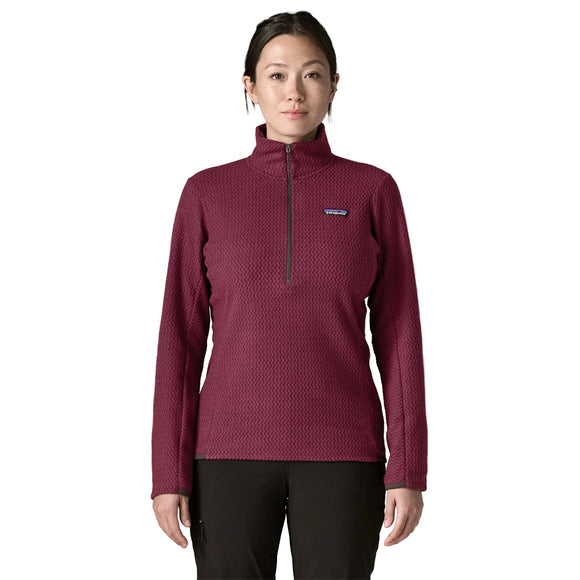 En kvinde iført en mørkerød, struktureret Patagonia R1 Air Zip Neck, Dame, Berry Fig – en langærmet fleecetrøje med kvartlås.