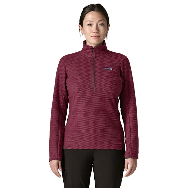 En kvinde iført en mørkerød, struktureret Patagonia R1 Air Zip Neck, Dame, Berry Fig – en langærmet fleecetrøje med kvartlås.