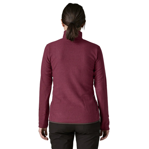 En person set bagfra, iført en dybrød Patagonia R1 Air Zip Neck, Dame, Berry Fig-fleece med et struktureret chevronmønster og sorte bukser.