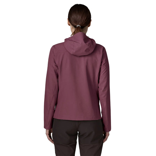 En person står med ryggen til kameraet og har en Berry Fig Patagonia R1 CrossStrata Hoody og mørke bukser på. Håret er bundet tilbage i en lav hestehale. Baggrunden er helt hvid.