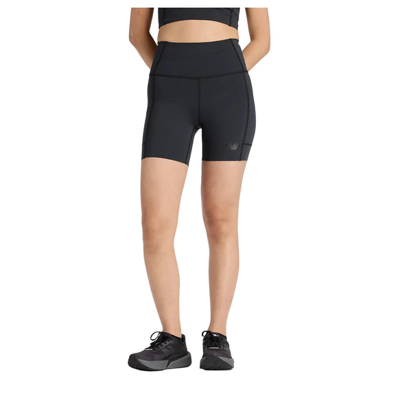 En person iført en sort atletisk crop top, New Balance RC Elite Storage Short 6" Dame i sort med opbevaringslomme og sorte New Balance sneakers står på en hvid baggrund. Personens hoved er ikke synligt på billedet.