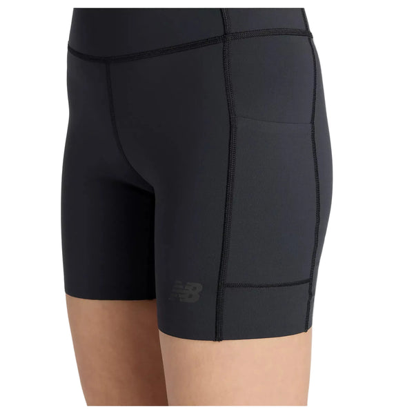 Nærbillede af en person iført sort New Balance RC Elite Storage Short 6" Dame med tætsiddende design, opbevaringslomme i siden, synlige sømme og New Balance-logoet nederst på venstre ben.